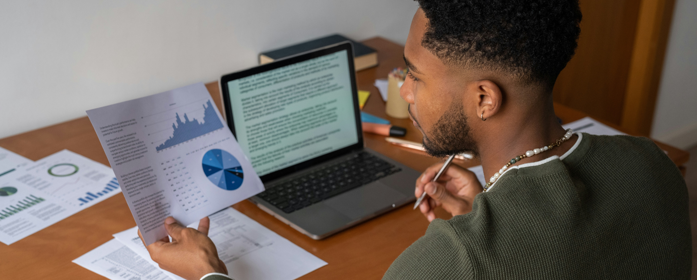 Une personne est assise à un bureau, tenant un document imprimé avec des graphiques et des tableaux.