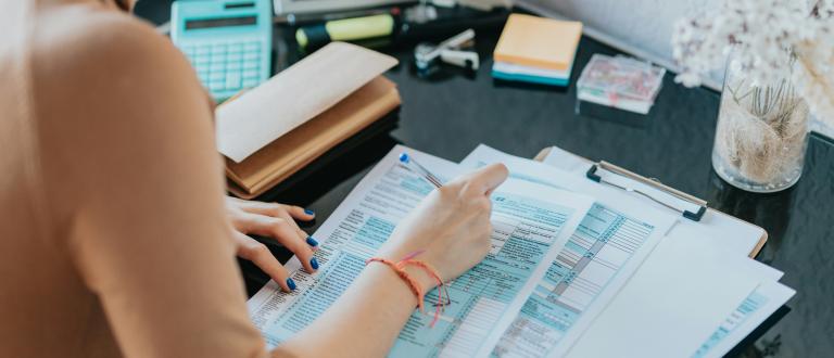a-woman-sitting-at-a-desk-working-on-a-piece-of-paper