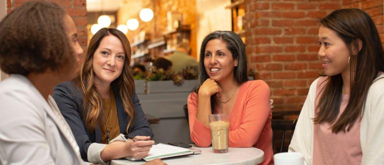Quatre femmes en conversation travaillent dans un café