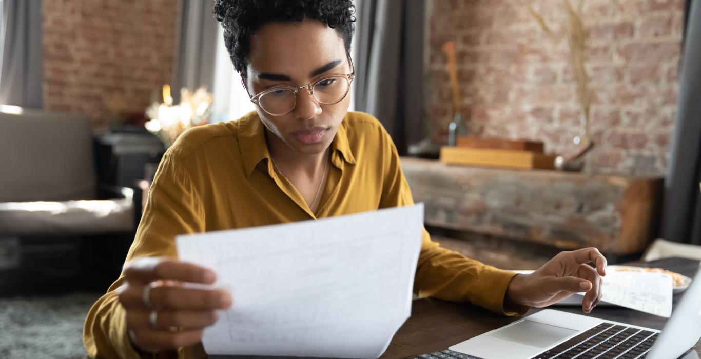 Focused woman in eyeglasses looking through paper documents