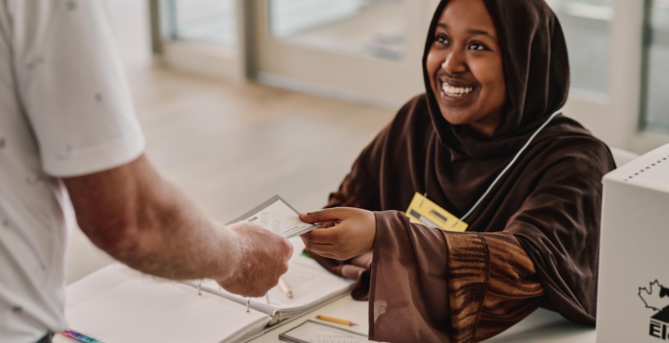 A poll worker checks the elector's eligibility to vote