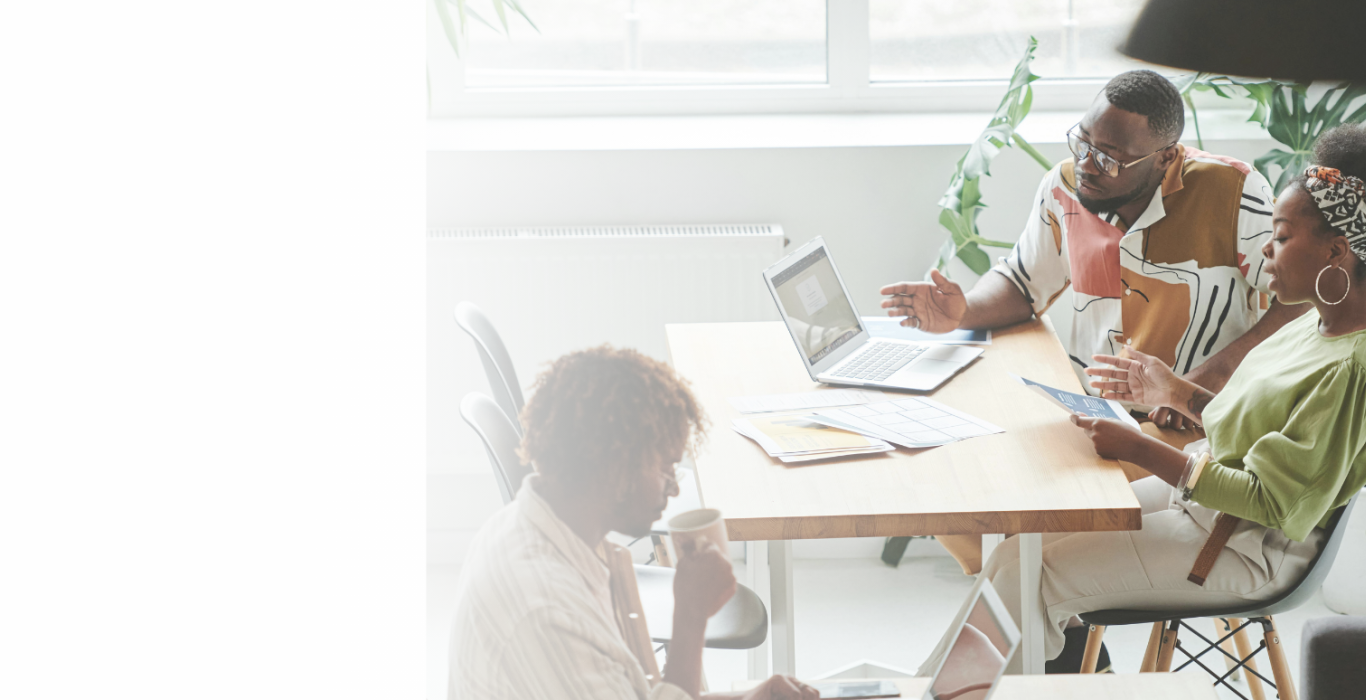 People collaborating at a table with a laptop and documents