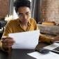 Focused woman in eyeglasses looking through paper documents