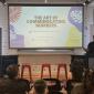 A speaker stands at a podium addressing an audience at an Imagine Canada event, with a screen behind them reading “The Art of Communicating Numbers” and event details for a PRISM Network Summer Social.